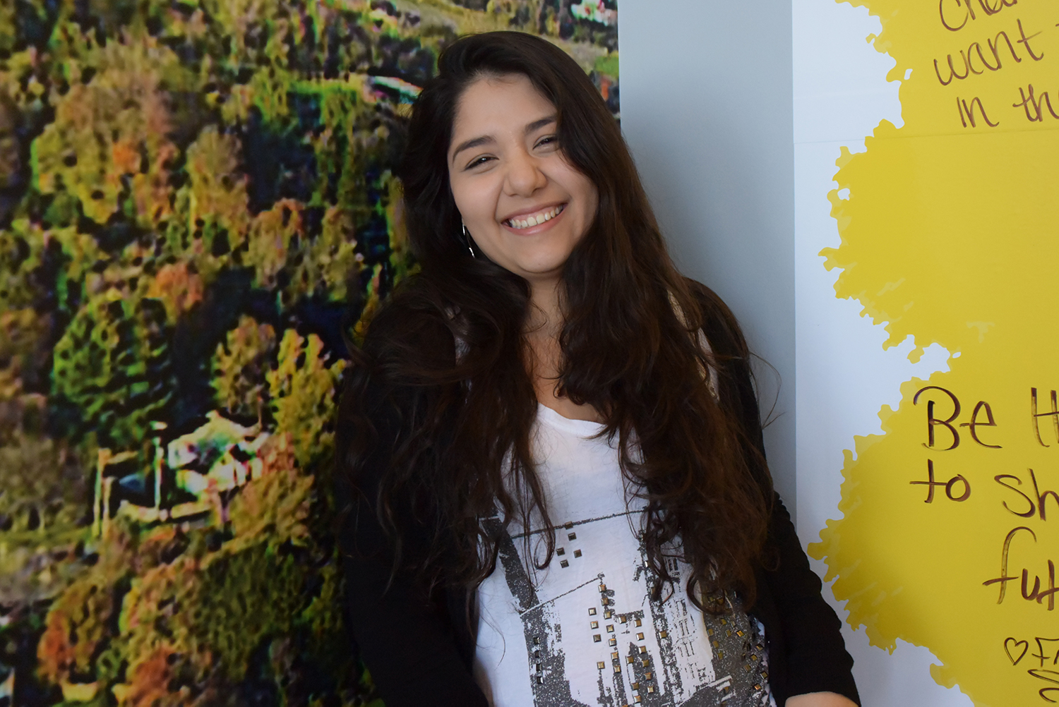 An OCC student in front of a nature mural