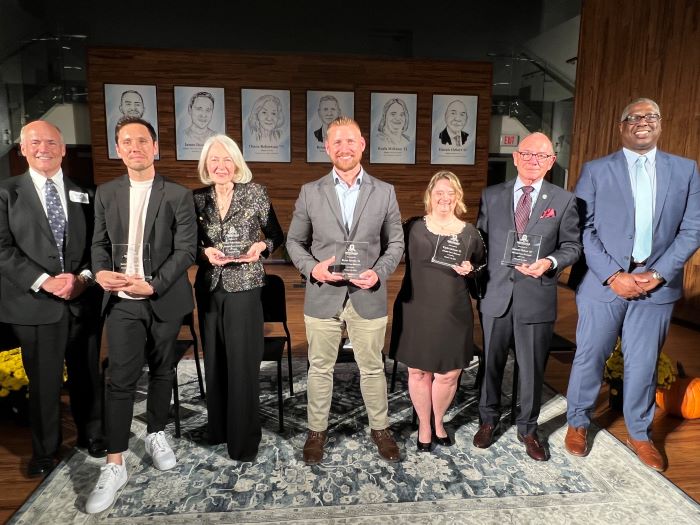On stage for the 2023 Alumni Faces ceremony are (left to right): emcee Glenn LaPoint '16, James Domroe '02, Diana Robertson '77, Bryan Morris '14, Kayla McKeon '22, Dennis Hebert '67, and OCC President Dr. Warren Hilton.