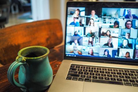 A Laptop opened to a Zoom Meeting with a Cup of Coffee Immediately Adjacent