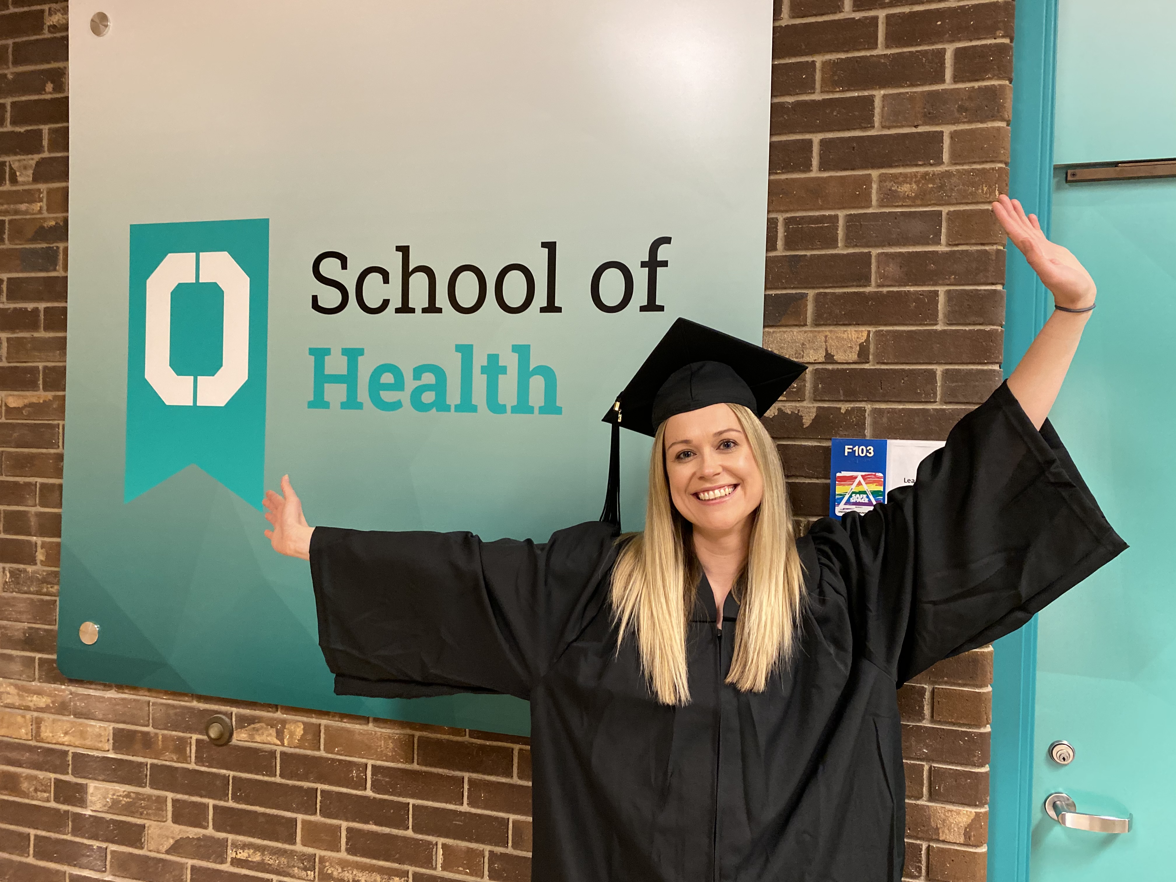 Woman standing in front of a sign that says School of Health 