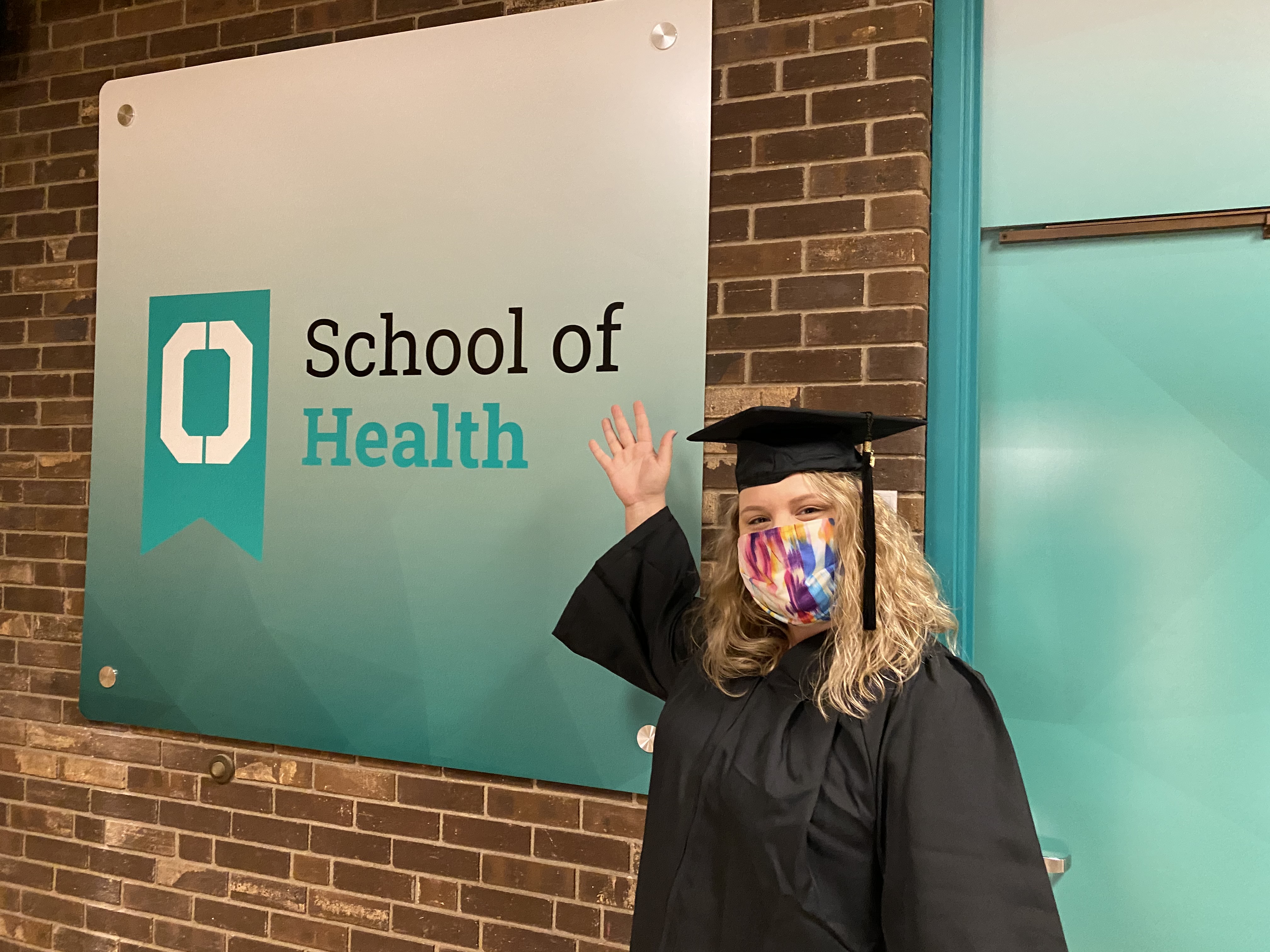 Woman standing in front of a sign that says School of Health 