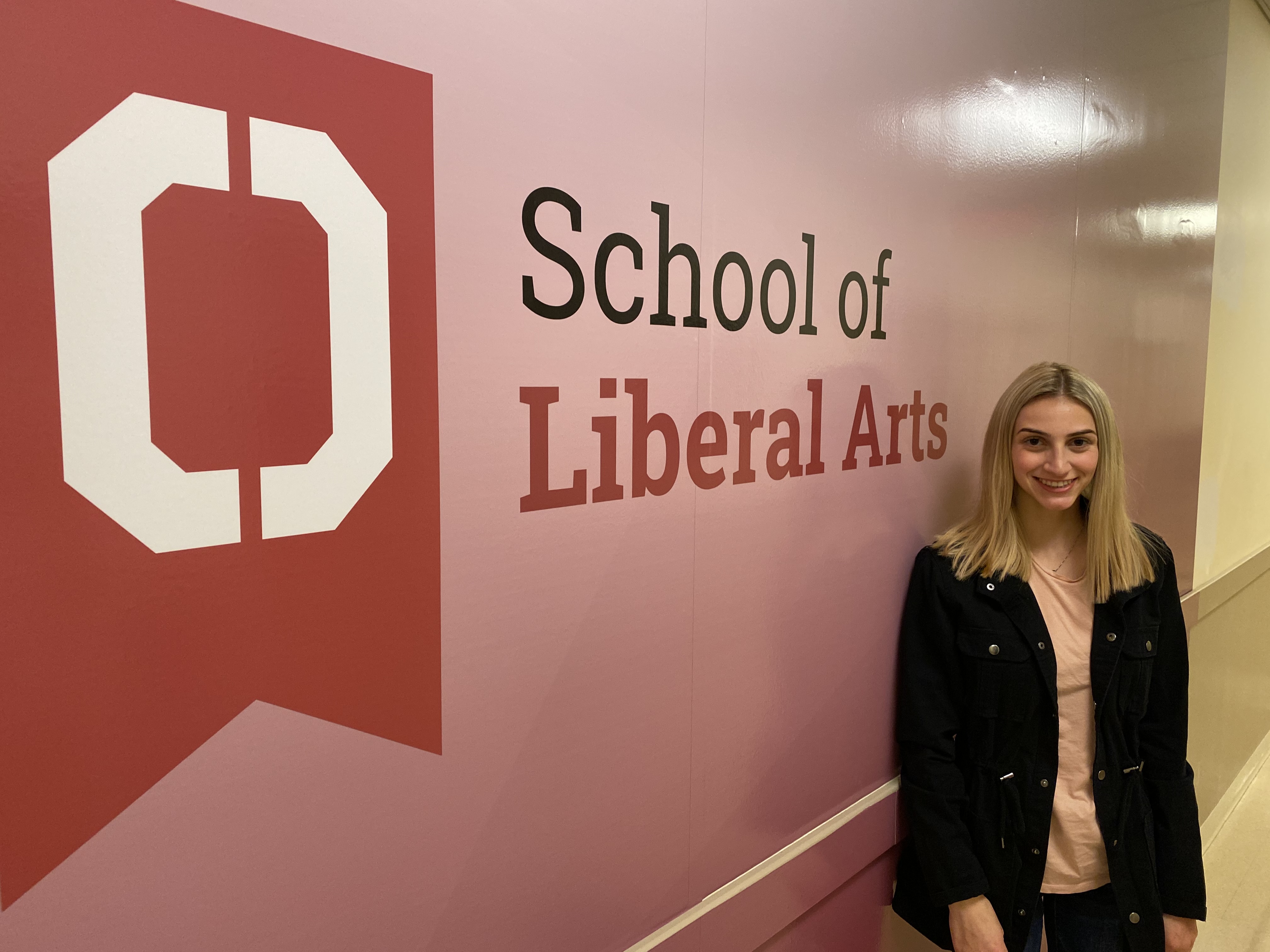 Woman standing in front of a sign that says School of Liberal Arts 