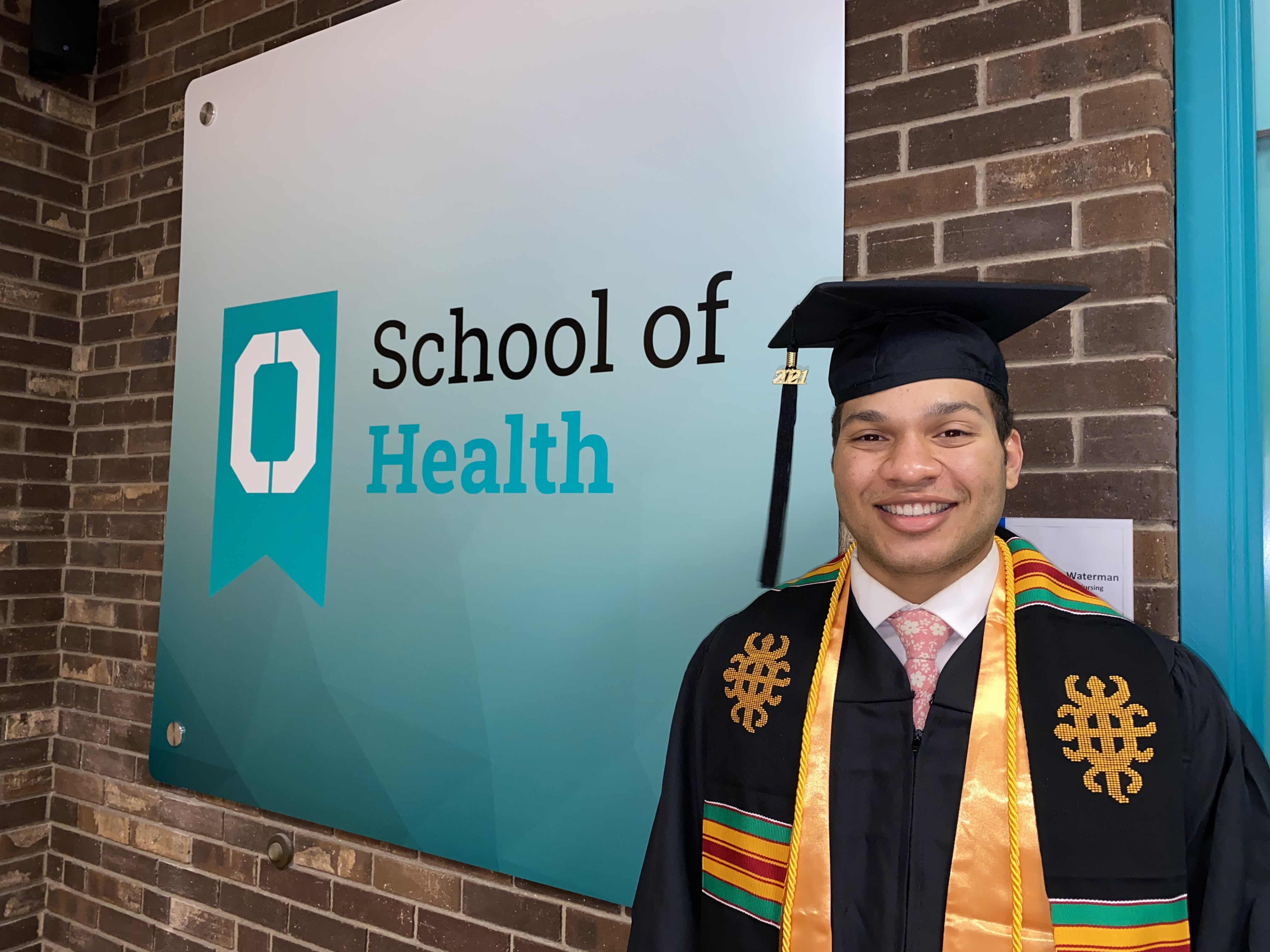 Man standing in front of sign that says School of Health 