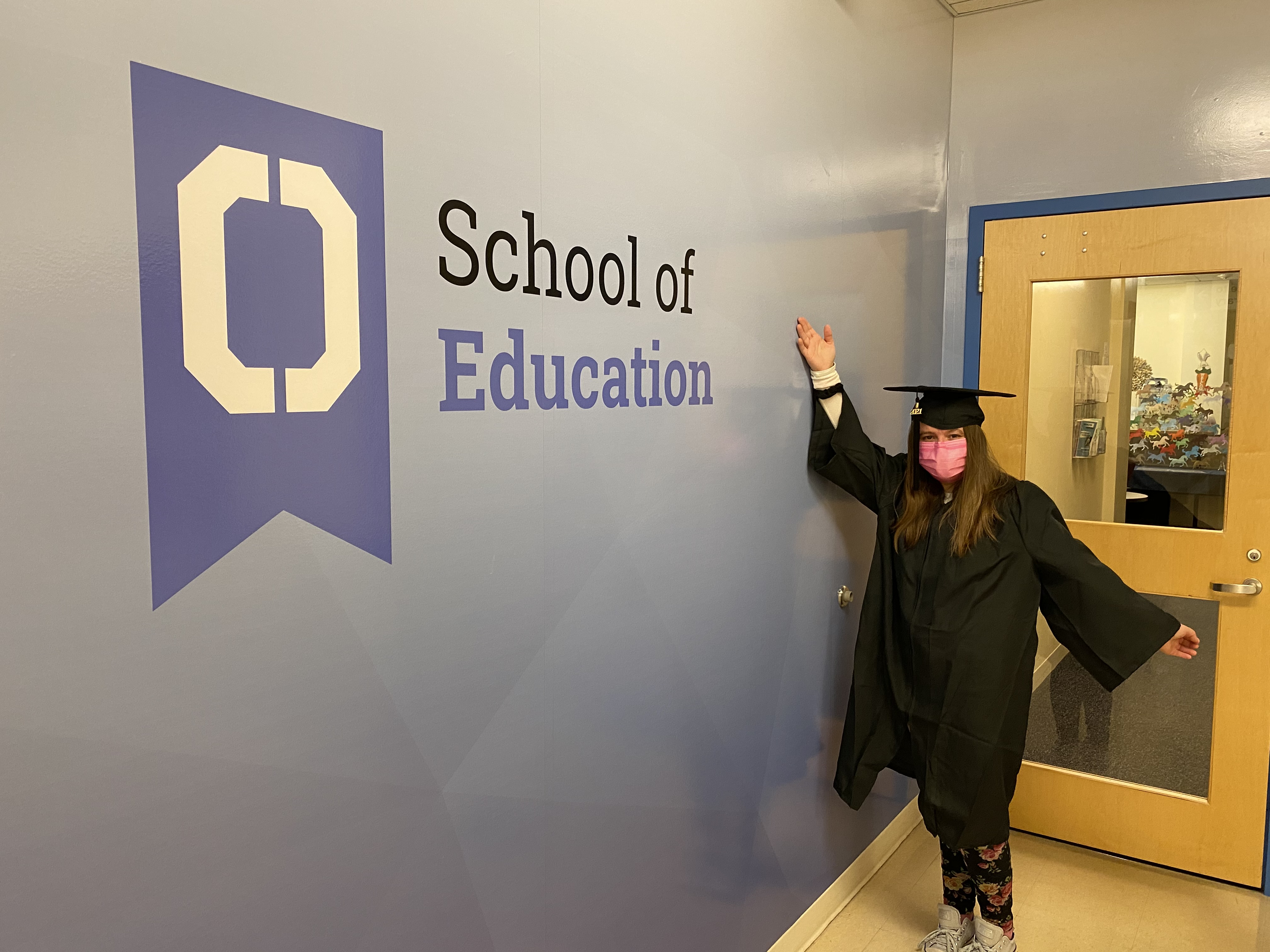Woman standing in front of a sign that says school of education 