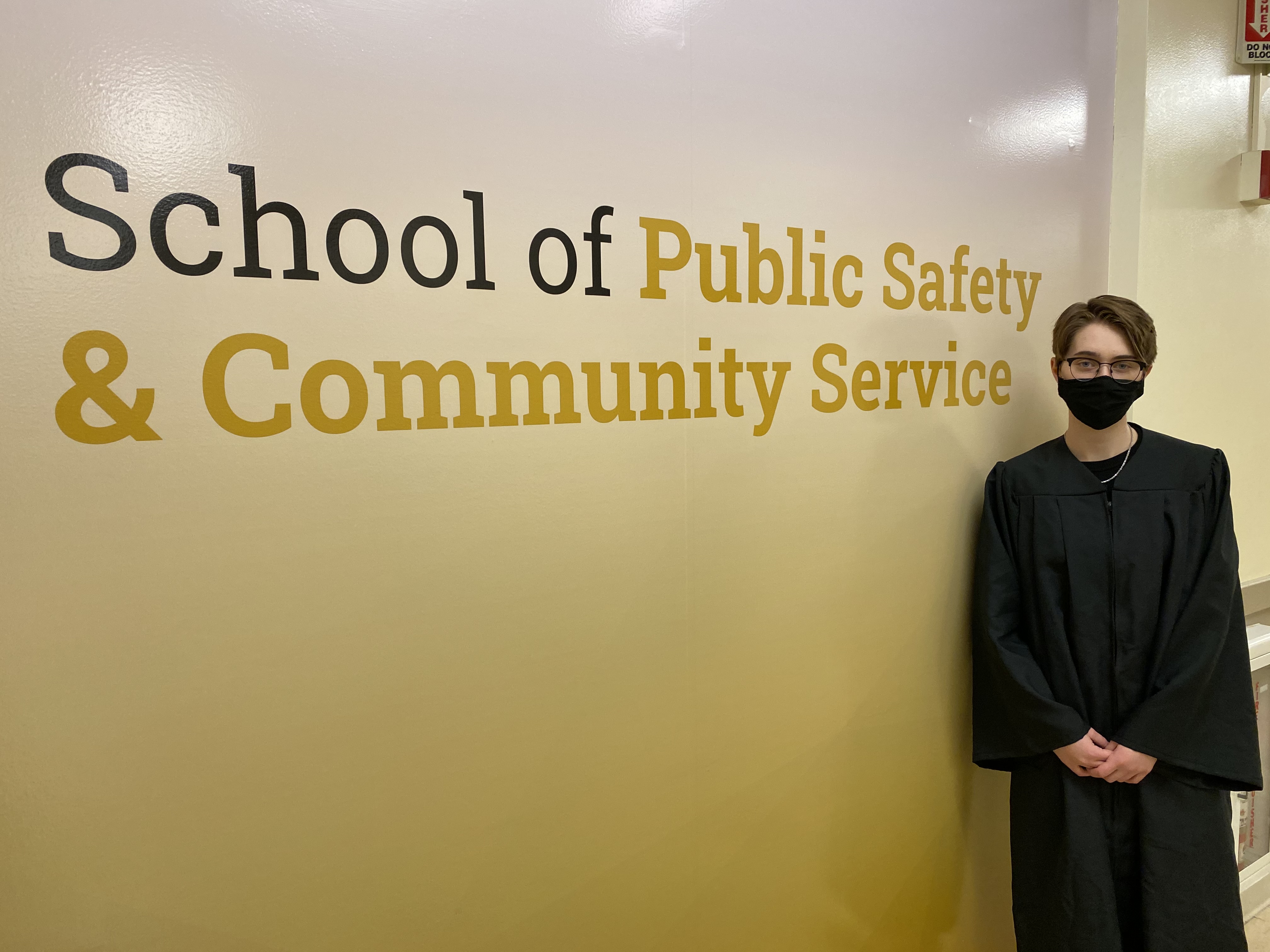 Woman standing in front of a sign that says "School of Public Safety & Community Service"