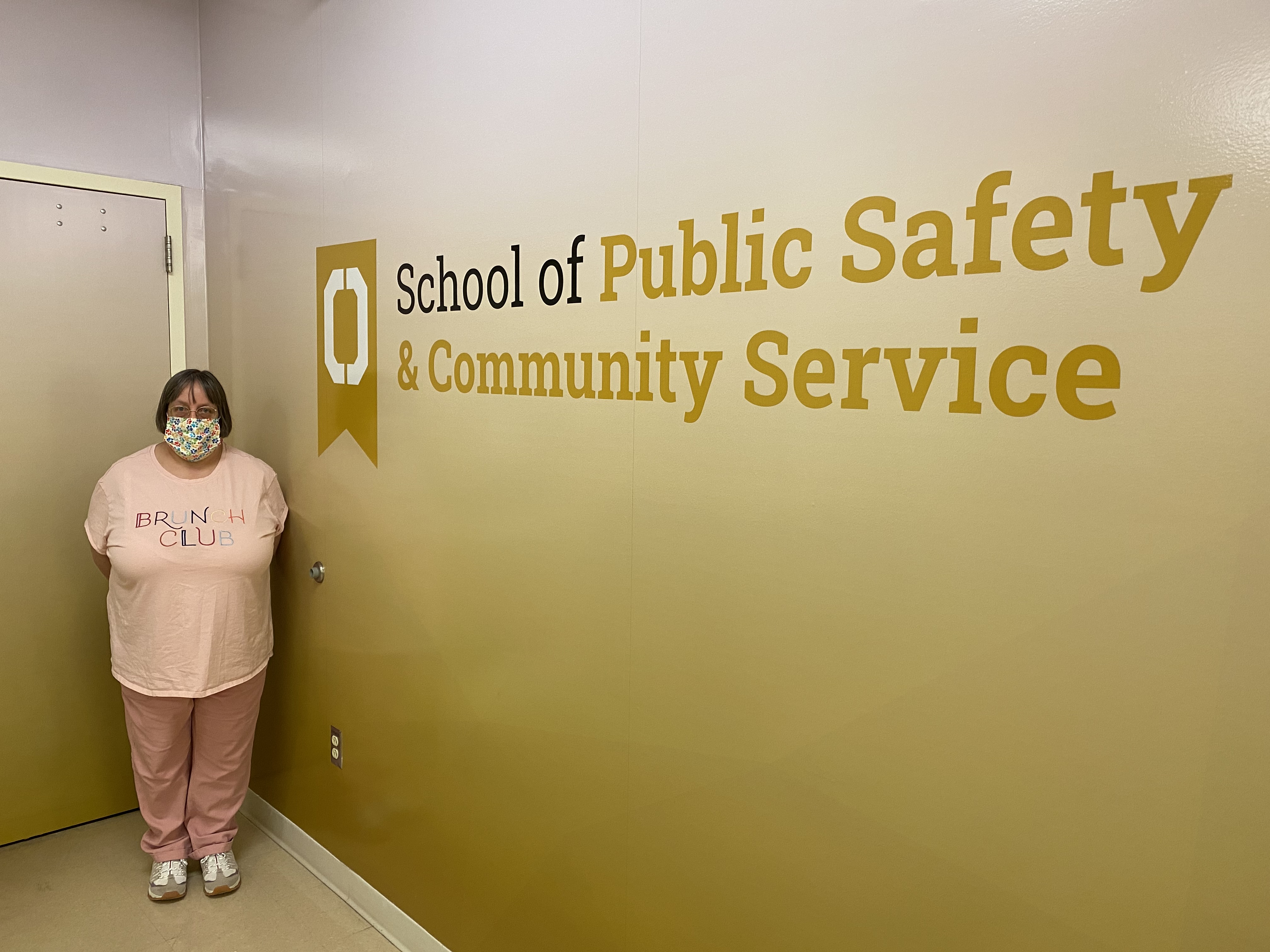 Woman standing in front of a sign that says "School of Public Safety & Community Service"