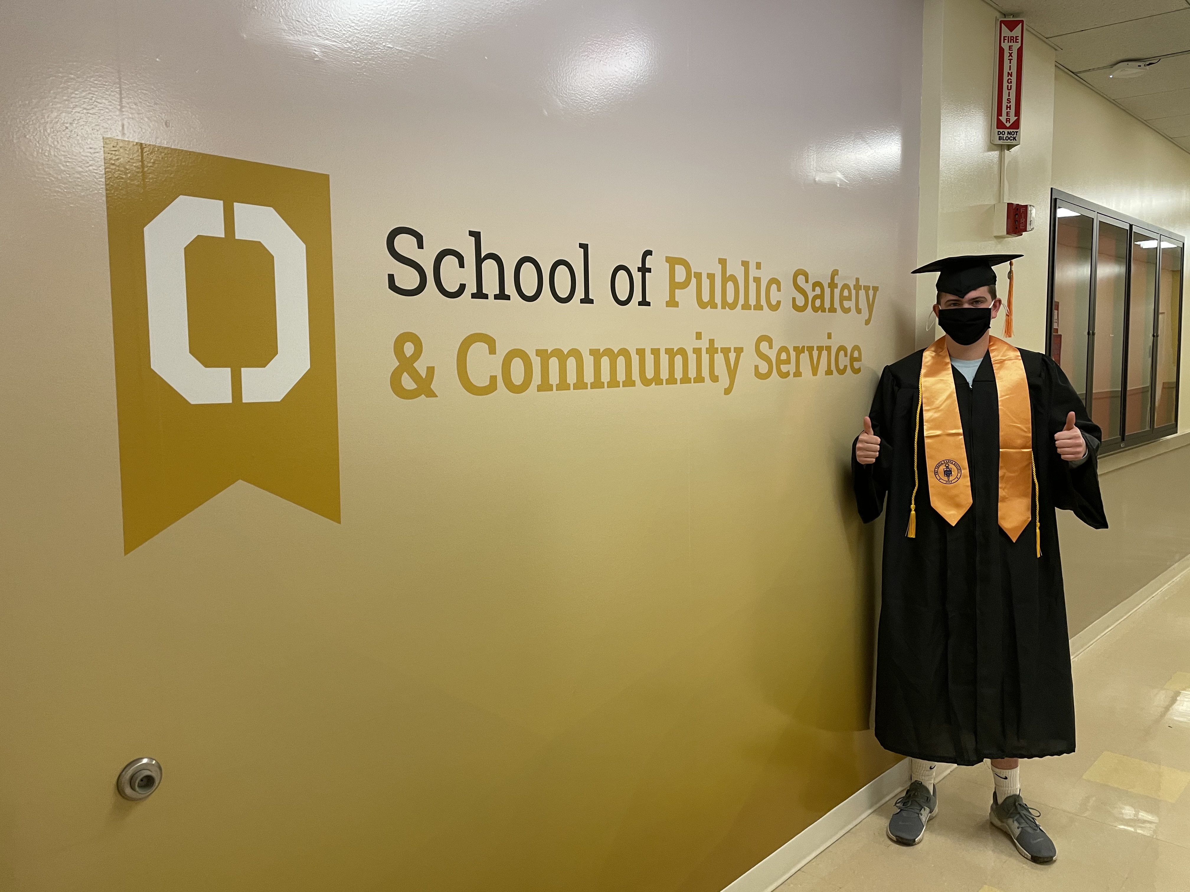 Man in front of a sign that says School of Public Safety and Community Service 