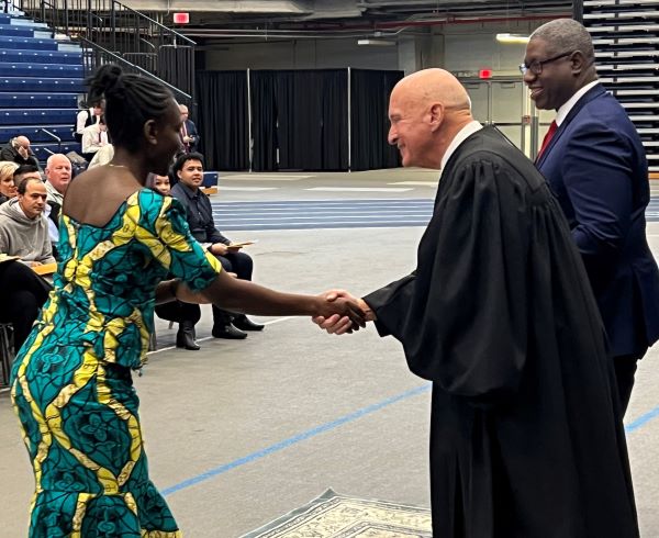 The Honorable David E. Peebles shakes the hand of a new American citizen. To his right is OCC President Dr. Warren Hilton.