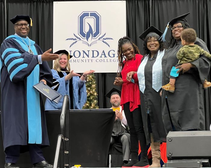 OCC's December Graduation celebration concluded with Barbara Wiggins (wearing light blue stole) and her daughter Tanisha Wiggins (holding her son Jonathan) receiving their Human Services degrees. They were joined on stage by Tanisha's sister, Alisha (wearing red and black) who completed her degree in December 2020 but didn't have a ceremony due to Covid. Joining them on stage are OCC President Dr. Warren Hilton and Provost Anastasia Urtz.
