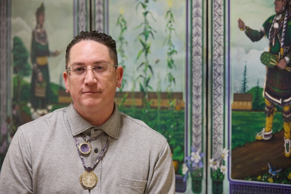 Lazore '14 sits in front of his newest artwork on the OCC campus, "Haudenosaunee Harvest." It's displayed in the new Indigenous Student Center on the second floor of Mawhinney Hall.