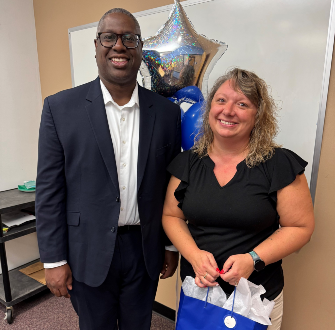Becky Buff standing next to Dr. Warren Hilton with a gift bag and a balloon