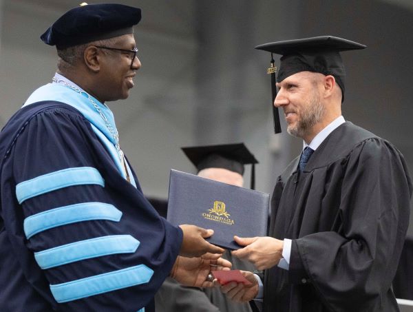 Entrepreneur Chedy Hampson (right) receives his degree from Onondaga Community College President Warren Hilton (left).