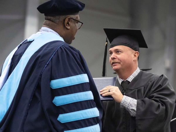 Onondaga County Undersheriff Jeffrey Passino (right) receives his degree from Onondaga Community College President Warren Hilton (left).