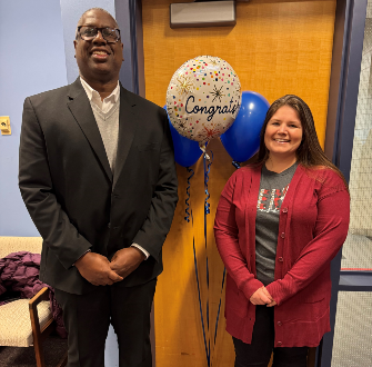 Meghan Peryea standing next to Dr. Warren Hilton with a gift bag and balloons