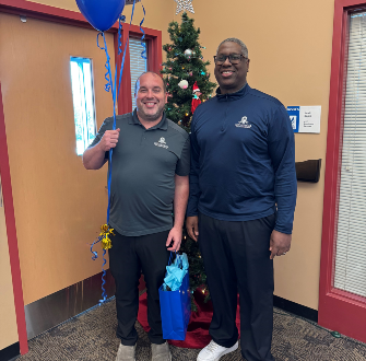 Ted Mathews standing next to Dr. Warren Hilton with a gift bag and balloons