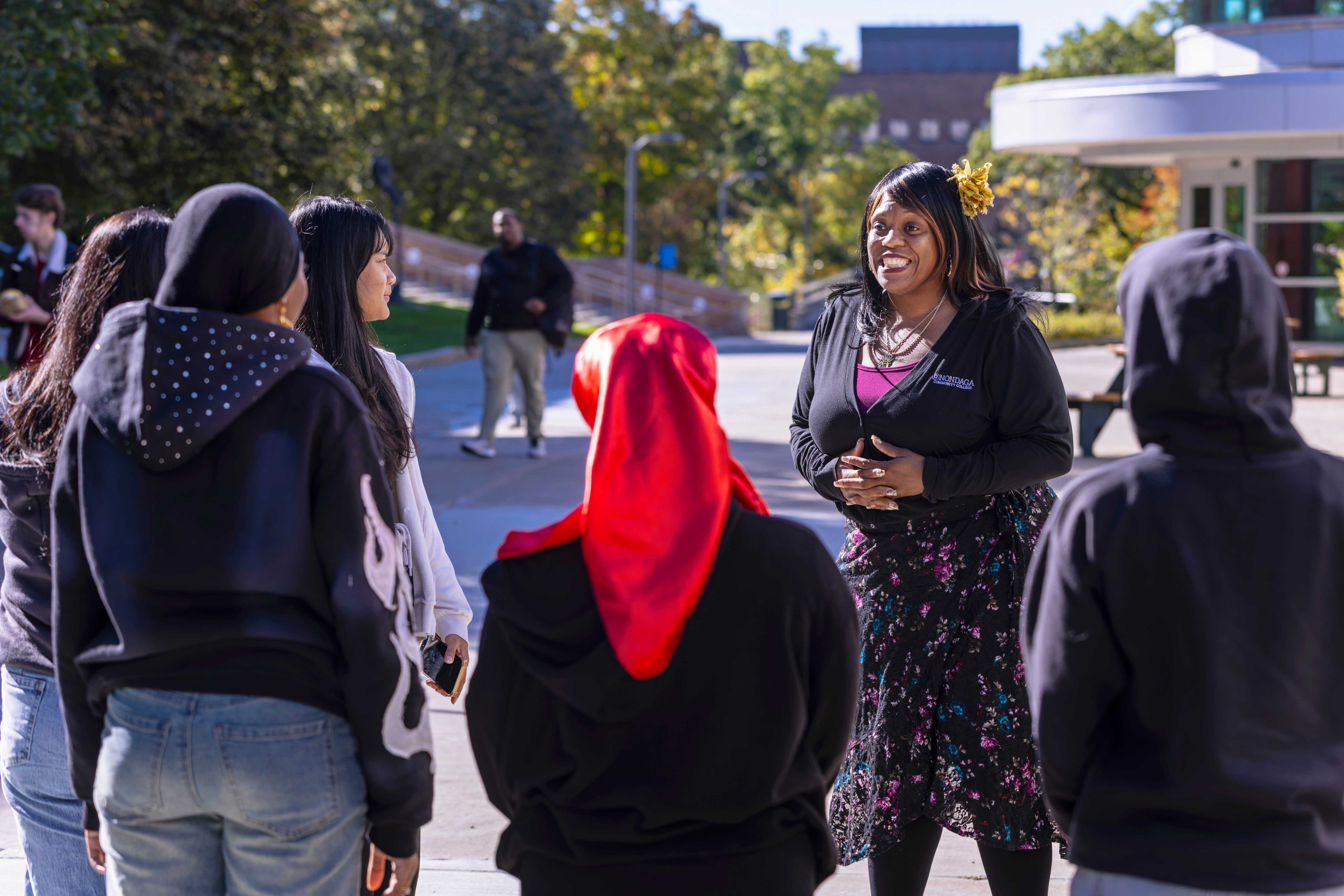 A guide speaks with a small group of students on a campus walkway.