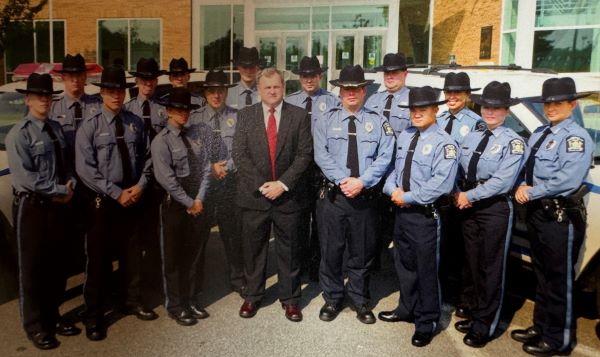 OCC's original Campus Safety team is pictured outside the Whitney Applied Technology Center in 2007. Director Frank Lawrence is in the center of the picture wearing a suit and tie. Yung is in the front row, and is the second officer to the right of Lawrence.