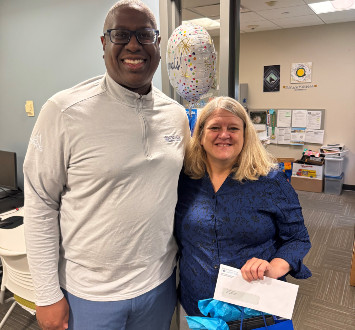 Dana Marzynski standing next to Dr. Hilton with balloons and a gift bag.