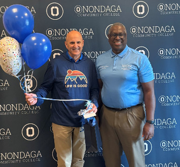 Roger Mirabito standing next to Dr. Hilton with balloons and a gift bag.