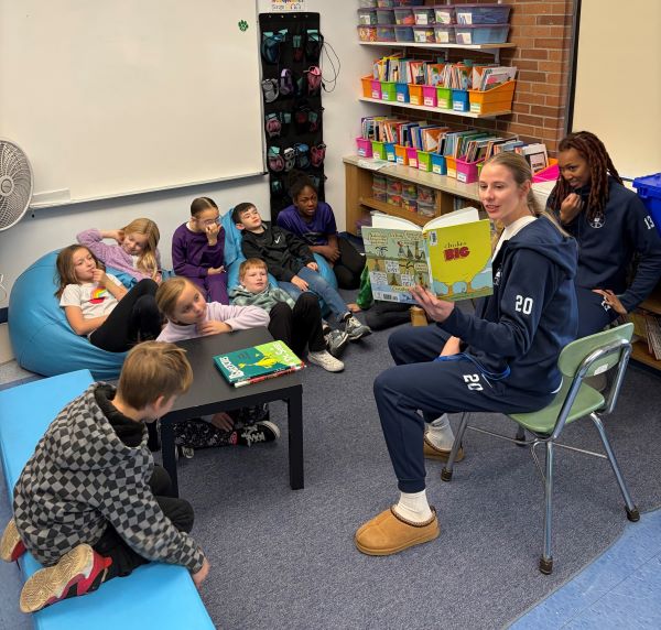 OCC Women's Basketball players Mary Hamer (#20) and Morgan Vasquez (#13) read to students at Wheeler Elementary School.