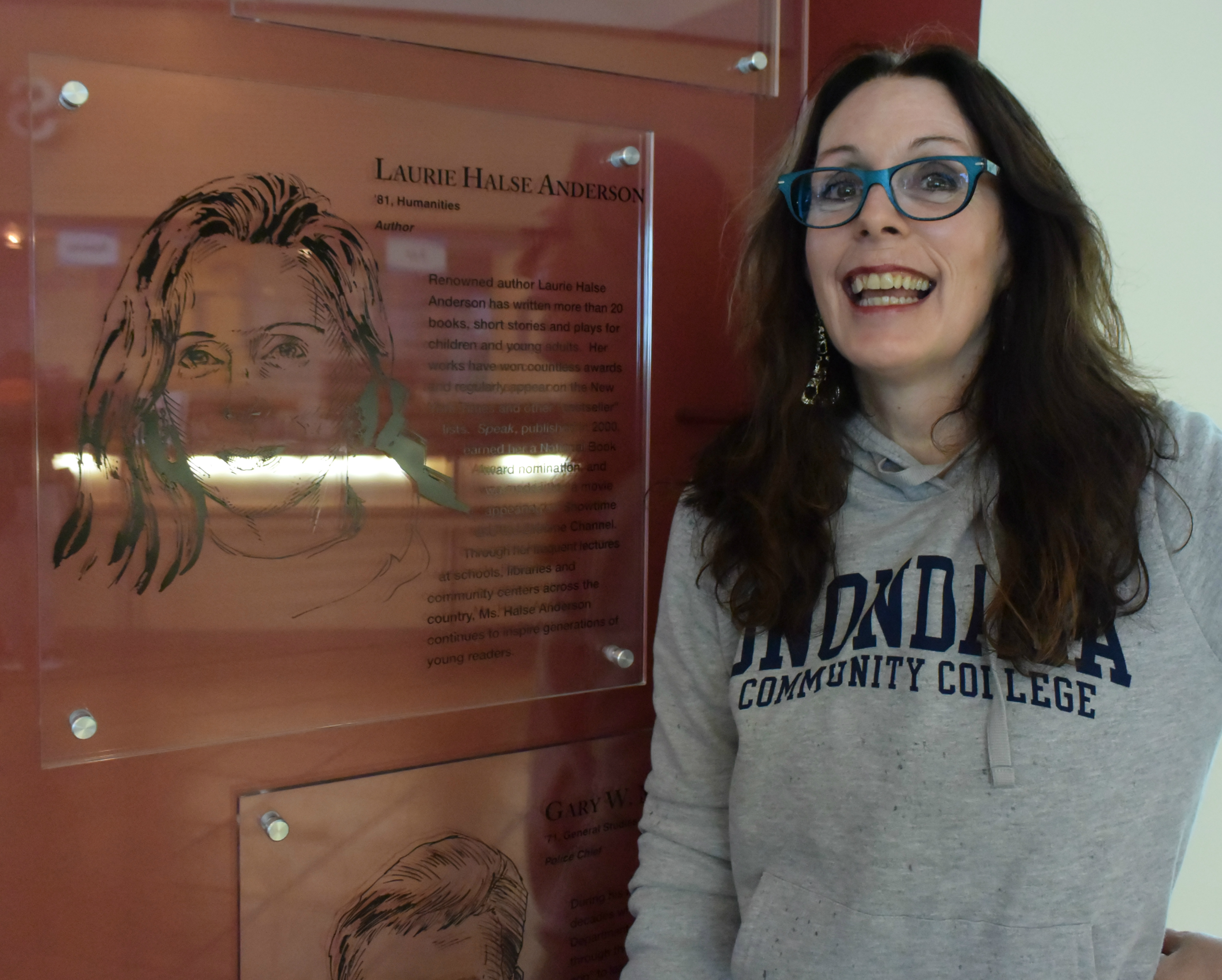 Anderson next to her Alumni Faces acrylic which hands in the Gordon Student Center across from the Student Central counter.