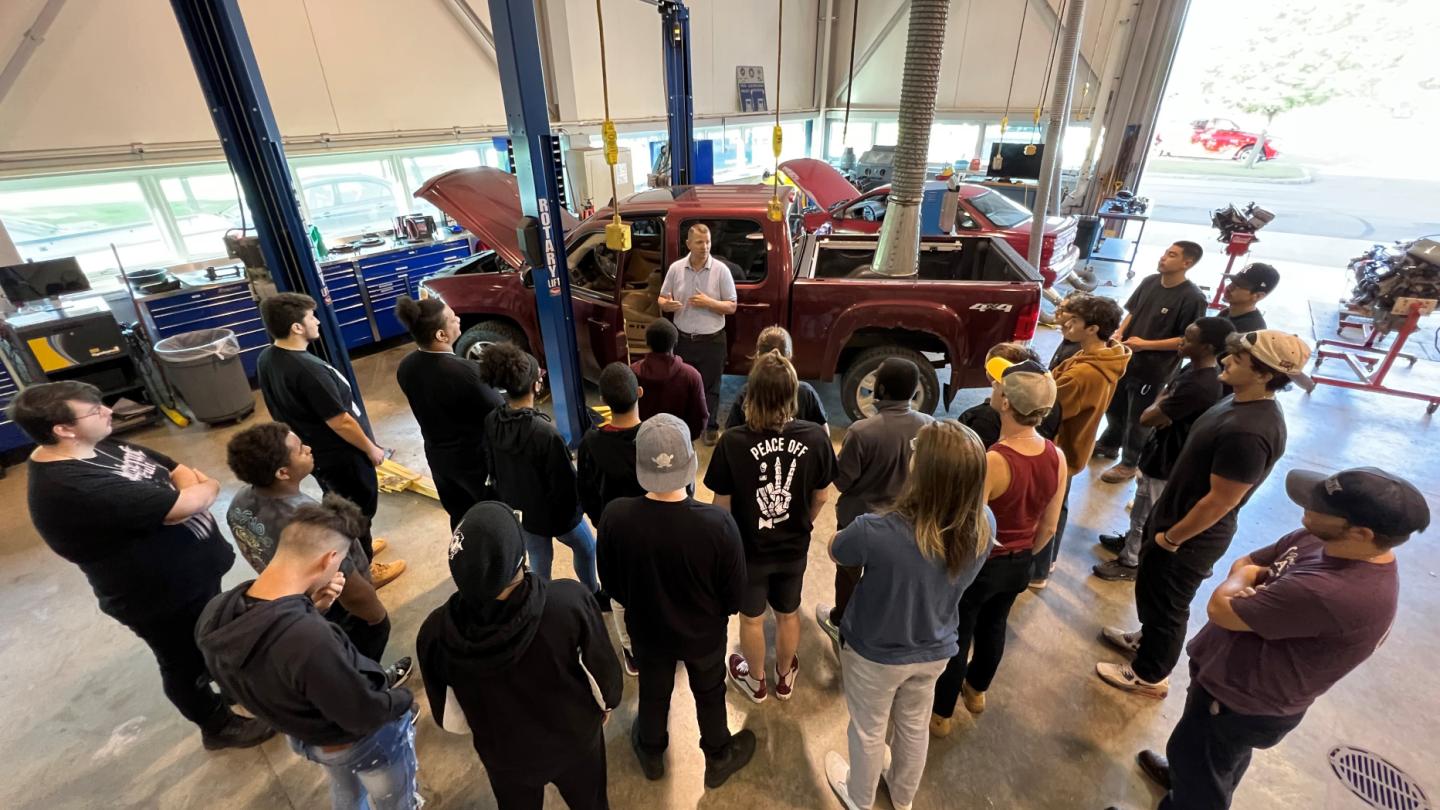 Professor Ryan Beckley (center, in gray shirt) speaks with students in the Automotive Technology lab in the Whitney Applied Technology Center.