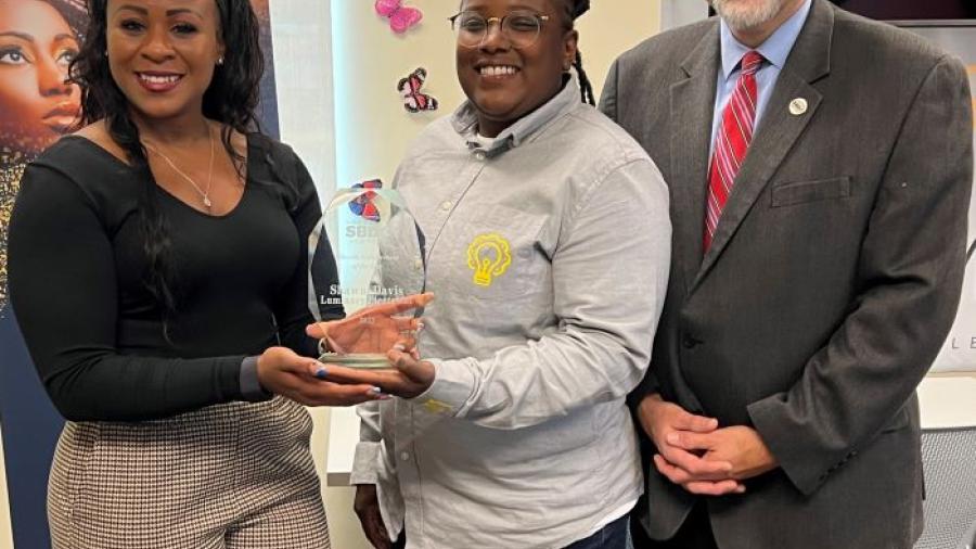 Shawni Davis (center) receives New York State Small Business Development Center's 2023 Minority Entrepreneur of the Year Award from Sonya Smith (left) of the NYS SBDC and Bob Griffin of the SBDC office headquartered at OCC (right).
