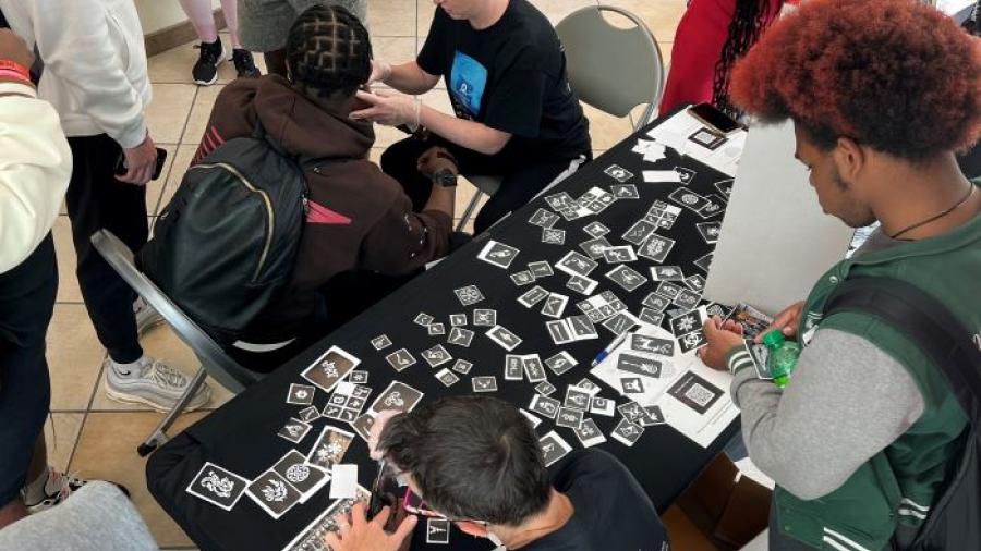 OCC's Shannon Nolan (upper center wearing black t-shirt) and Colleen Stevens (lower center wearing black t-shirt) apply henna tattoos on students arms during Unity Day festivities.