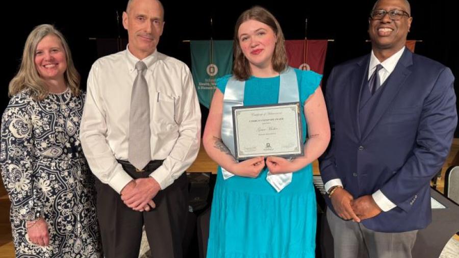 Grace Meeker (holding certificate) was named Curriculum Honoree in the Business Administration degree program. She's pictured with (left to right) Provost Anastasia Urtz, Professor JT Ryan, and President Warren Hilton.