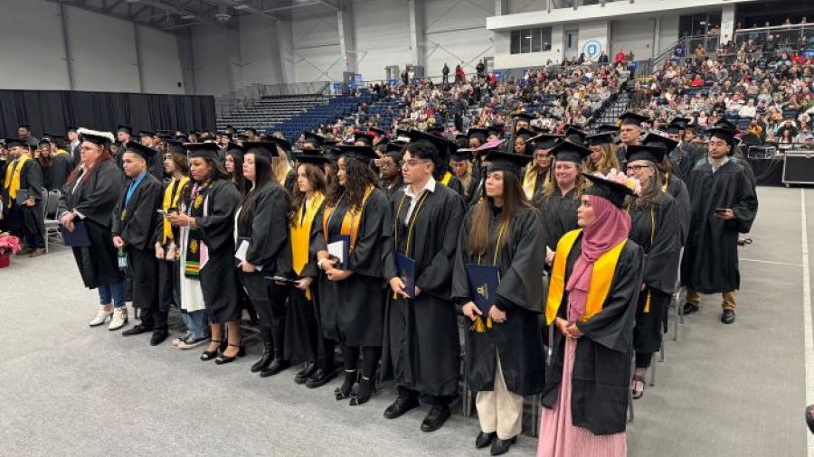 Onondaga Community College's newest alumni stand with their degrees before processing out of the SRC Arena.