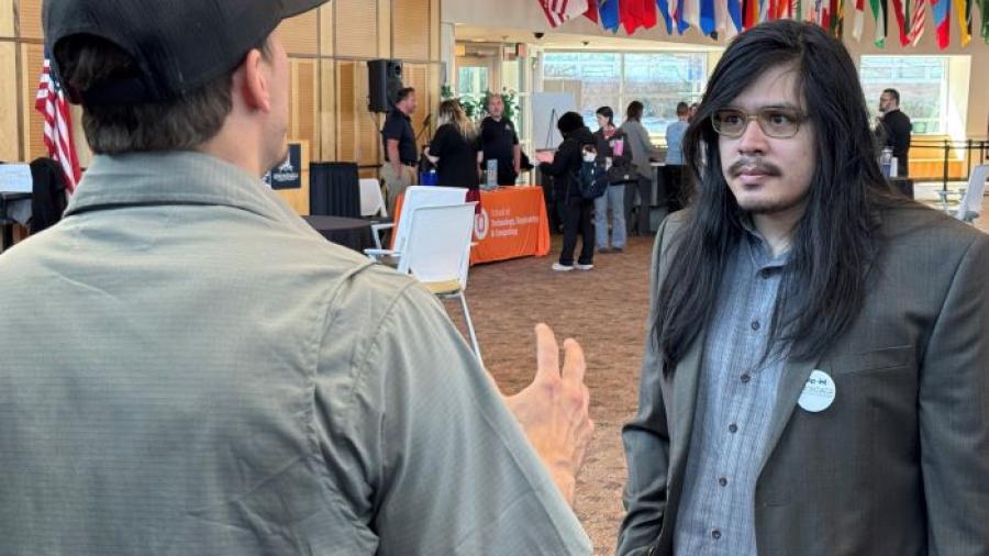 Onondaga Community College Welding major Ricky Stephens (right) speaks with a representative of Industrial Fabricating Corp at the STEM Career Showcase in the Gordon Student Center Great Room.
