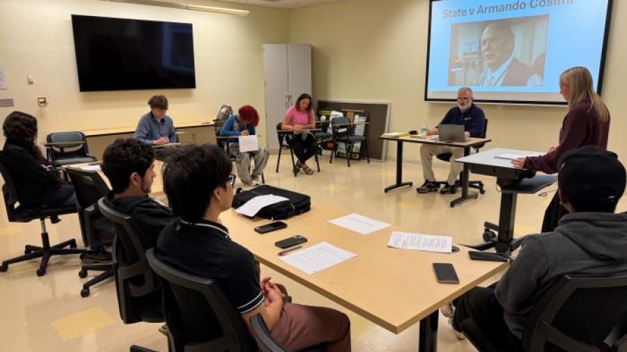 Student and prosecuting attorney Peyton George (standing, right) delivers her opening statements as part of the Criminal Investigations class final exam. Seated in front of the screen is Professor Pete Patnode who is acting as judge for the proceedings. 