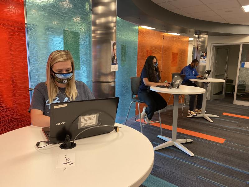 Three students sitting in the learning center with latops open doing work