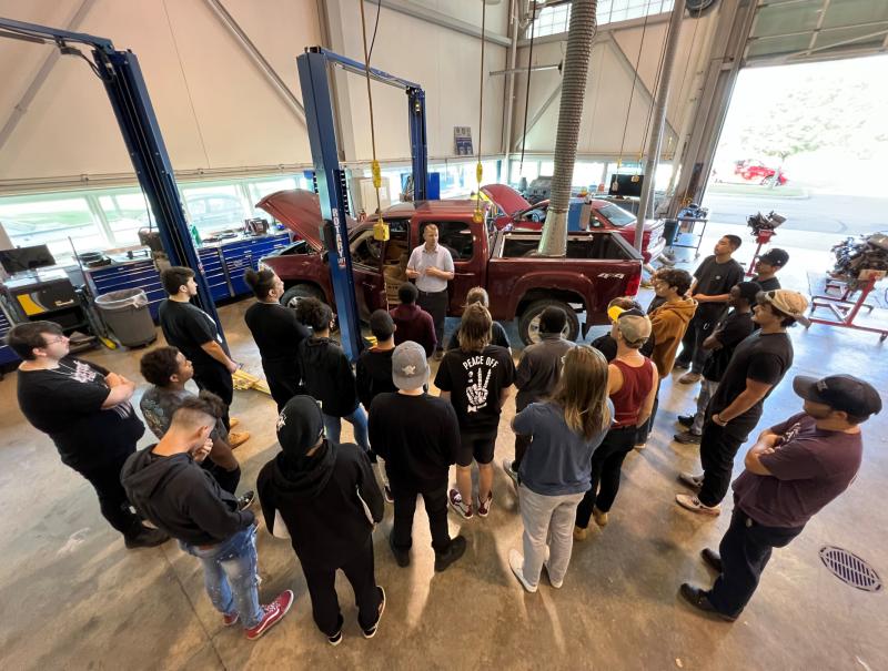Professor Ryan Beckley (center, in gray shirt) speaks with students in the Automotive Technology lab in the Whitney Applied Technology Center.