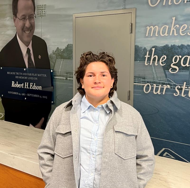 Giuliana Portolesi came to OCC from Spokane, Washington to play goalie on the Women's Lacrosse team and is this year's Rob Edson Scholarship recipient. She's pictured in front of a wall dedicated to Edson.