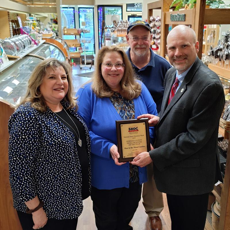 Man in the Moon Candies in Oswego receives the Oswego County Small Business of the Year Award. Pictured are (left to right) Kellie Greene, OCC SBDC Business Advisor, Amy Lear and Paul Lear of Man in the Moon Candies, and Bob Griffin, OCC SBDC Regional Director.