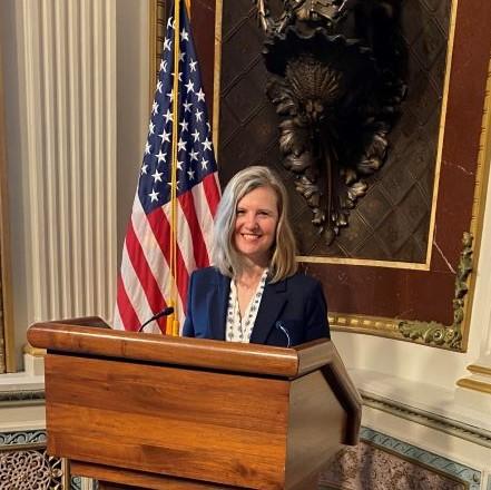 Onondaga Community College Provost and Senior Vice President Anastasia Urtz poses for a picture at a podium in the Eisenhower Building before speaking at the White House.
