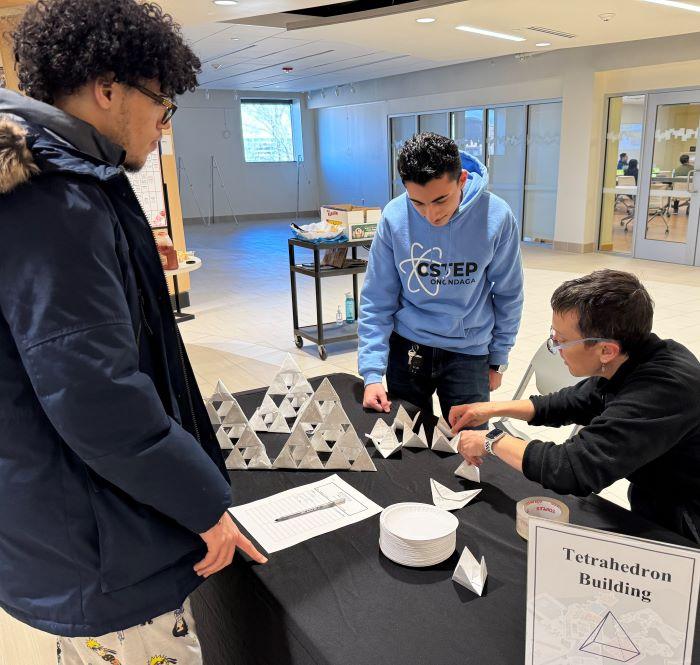 OCC's Colleen Stevens (seated) helps students at the Tetrahedron Building station as Part of Louis Stokes Day. They are pictured in the lobby of Coulter Hall.