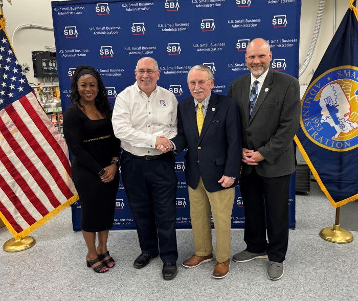 Mike Mowins (white shirt) is presented with the New York Veteran Owned Small Business of the Year Award by Paul Brooks of OCC's SBDC. Also pictured are (left) New York State SBDC Director Sonya Smith and (right) OCC SBDC Regional Director Bob Griffin.