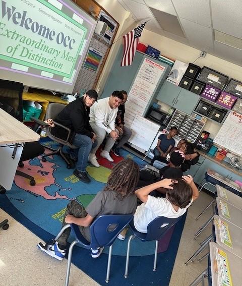 Members of Onondaga Community College's Extraordinary Men of Distinction speak with students at Syracuse's Meachem Elementary School.