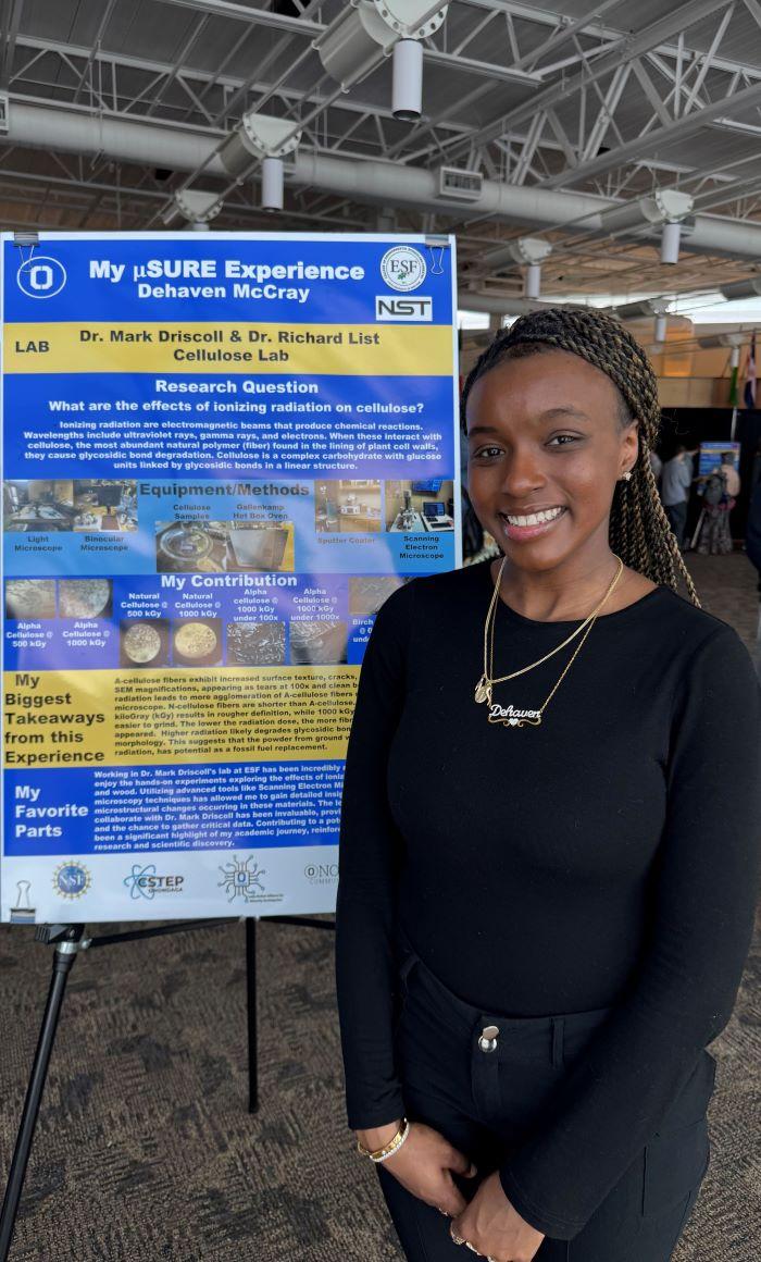 Dehaven McCray stands proudly in front of a poster board detailing her research as part of the USURE Science Symposium.