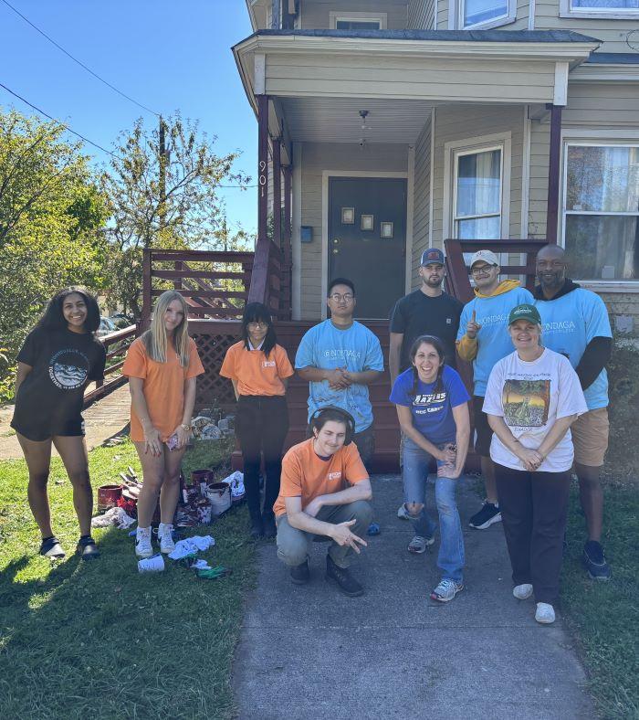 OCC community members pose for a picture in front of a freshly painted porch.