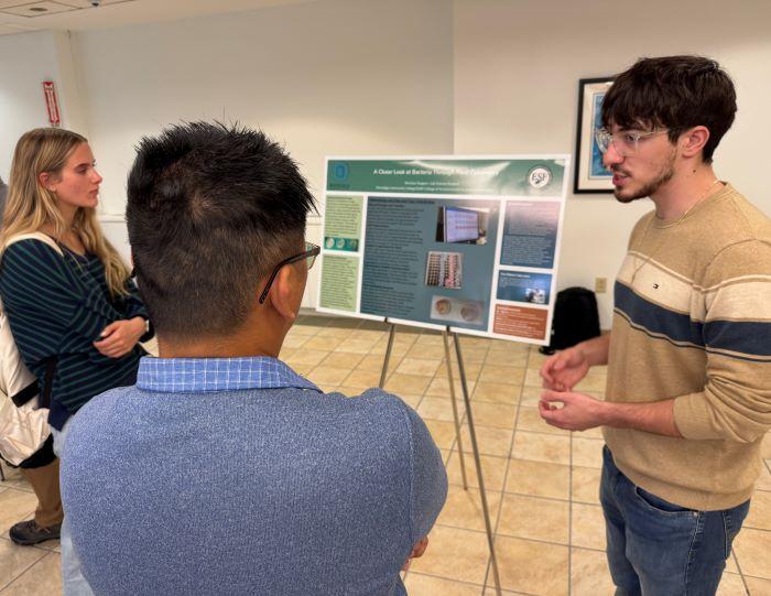 Nicholas Pangaro (right) discusses his research experience during a symposium in the Storer Auditorium Lobby. Pangaro is a Laboratory Sciences major who conducted research at SUNY-ESF during the summer.