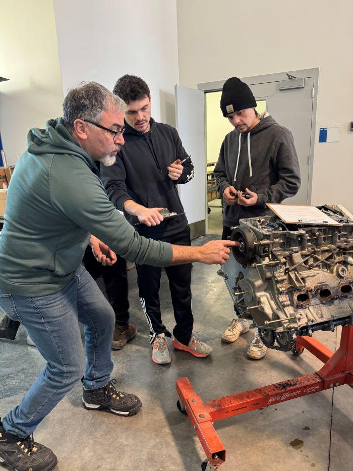 Automotive Technology Professor Jon Seargent (left) works with students Kellen Mulvihill (center) and Alex Shope (right) as they take apart a Ford 6 cylinder engine.