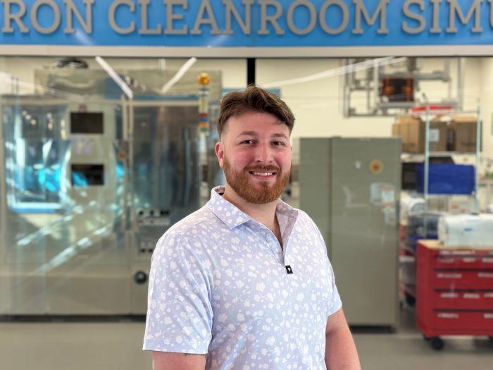Patrick Corbett '21 is an engineer at SRC and an Industrial Electricity professor at Onondaga Community College. He is pictured in front of the Micron Cleanroom Simulation Lab in OCC's Whitney Applied Technology Center.