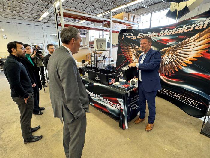 Michael Bower (right), a United States Marine Corps Veteran and owner of Eagle Metalcraft, shows one of the products his company makes.