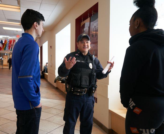 Onondaga Community College Peace Officer Rich Yung (center) speaks with students in the Gordon Student Center. Yung is the longest serving Peace Officer and the last original member of OCC's Campus Safety team.