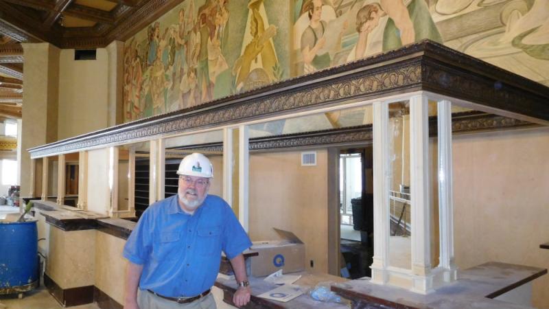Ed Riley pauses during the renovation of the old Hotel Syracuse. On the wall behind him is a famous mural which was uncovered during the restoration process.