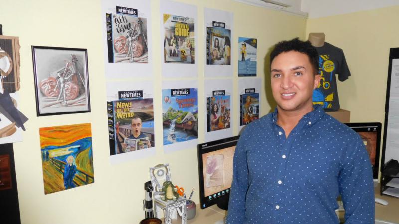 Minix with his collection of designed covers for the Syracuse New Times