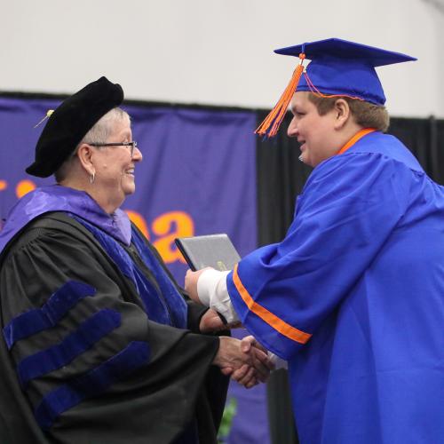 OCC President Dr. Casey Crabill (left) presents an associate degree to Caleb Jandolenko, a member of East Syracuse Minoa's class of 2022. Jandolenko was one of 17 students who received his high school diploma and college degree on the same day.